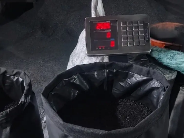 Activated carbon being filled into a lined sack on a digital weighing scale